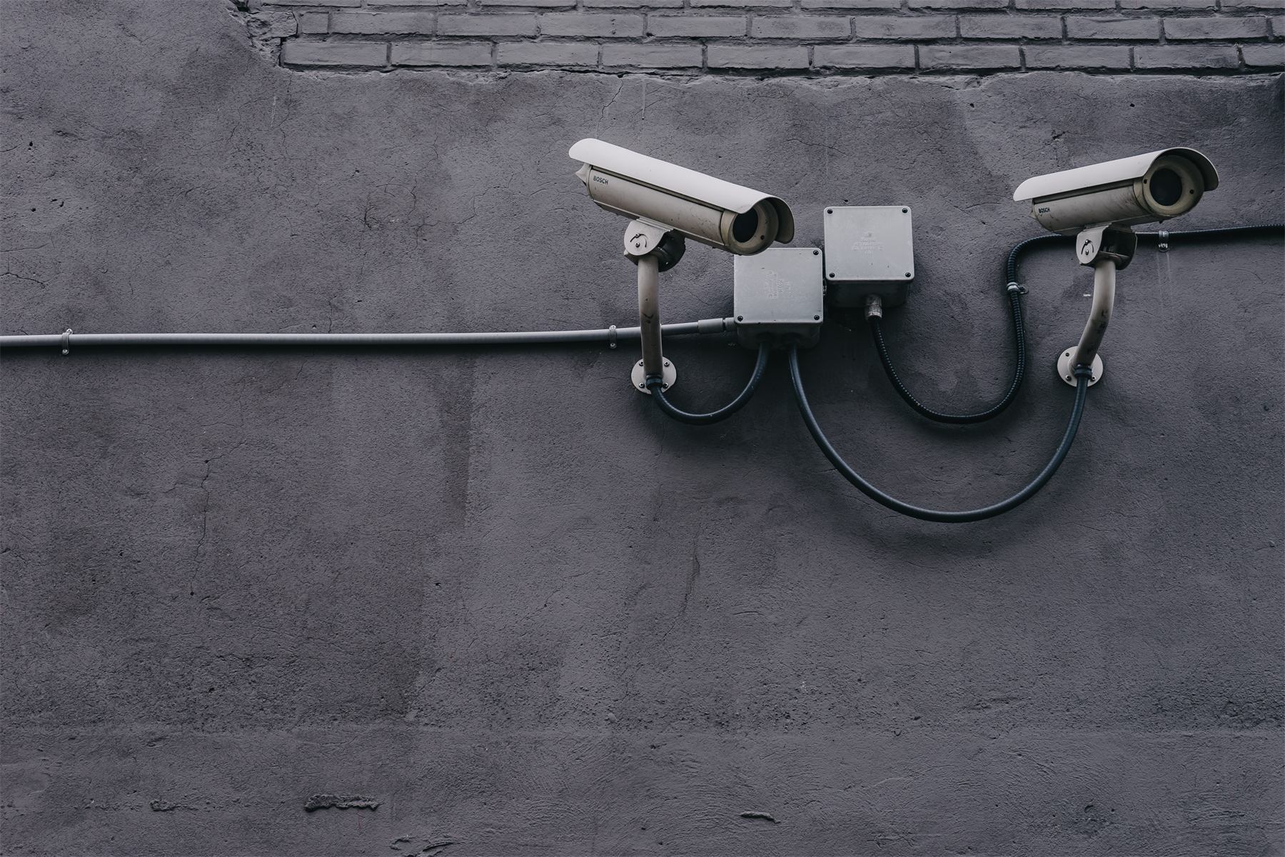 Two surveillance cameras on a gray facade