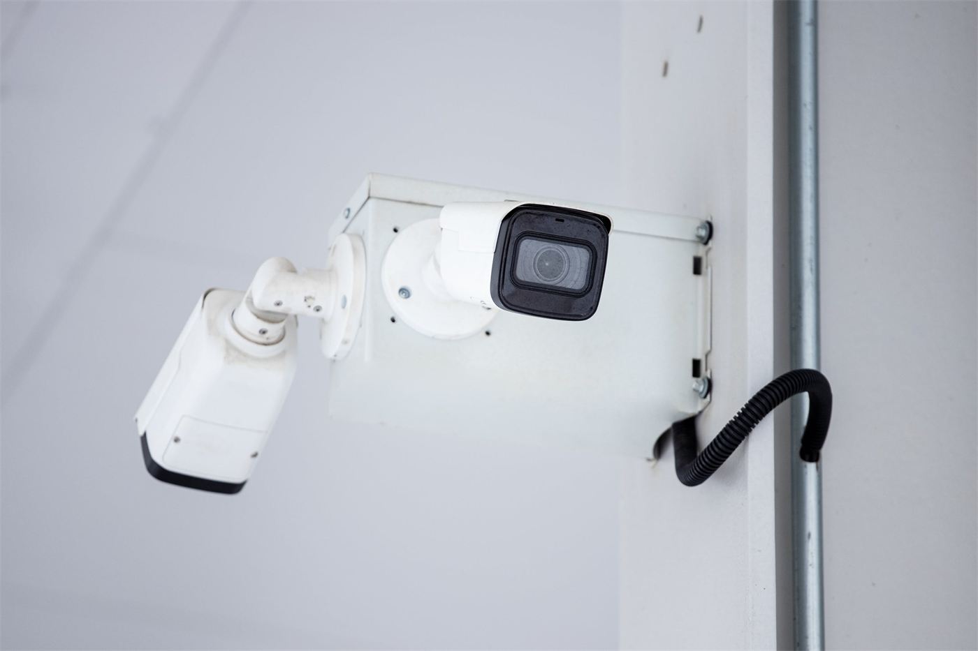 Two modern IP surveillance cameras mounted on a building wall