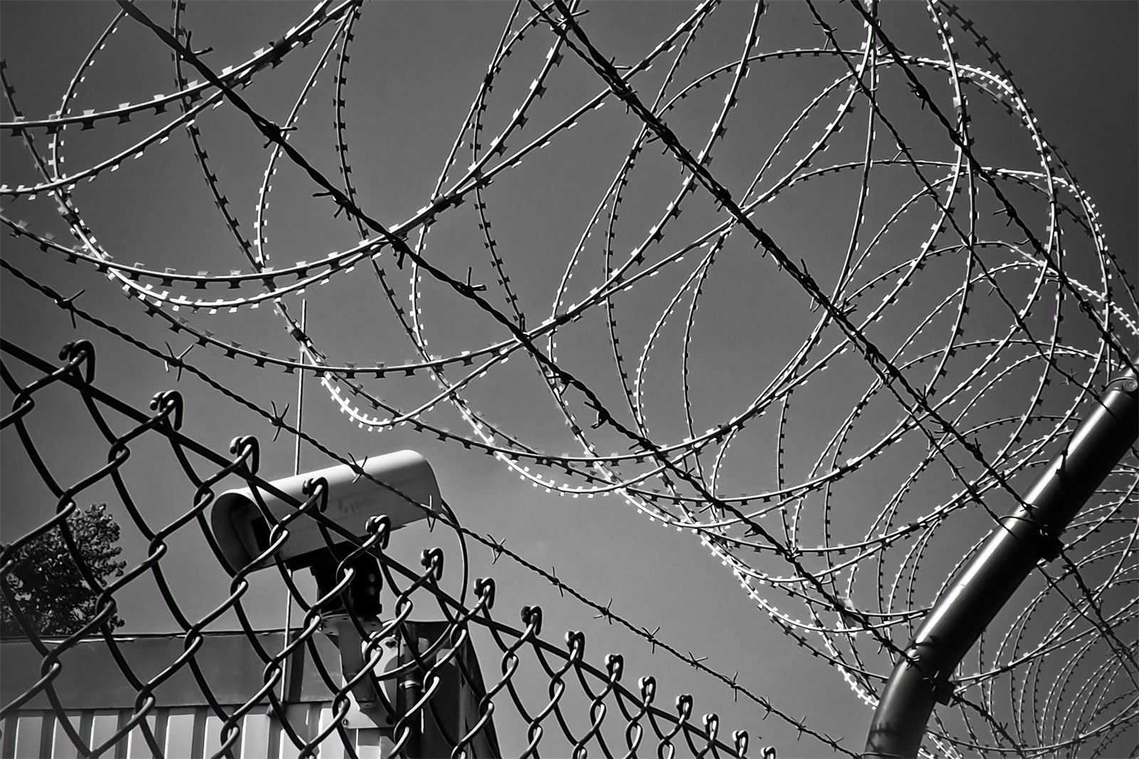 Surveillance camera behind a security fence with barbed wire
